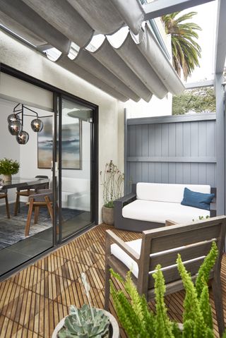 Small balcony with high wooden fence, an awning and seating