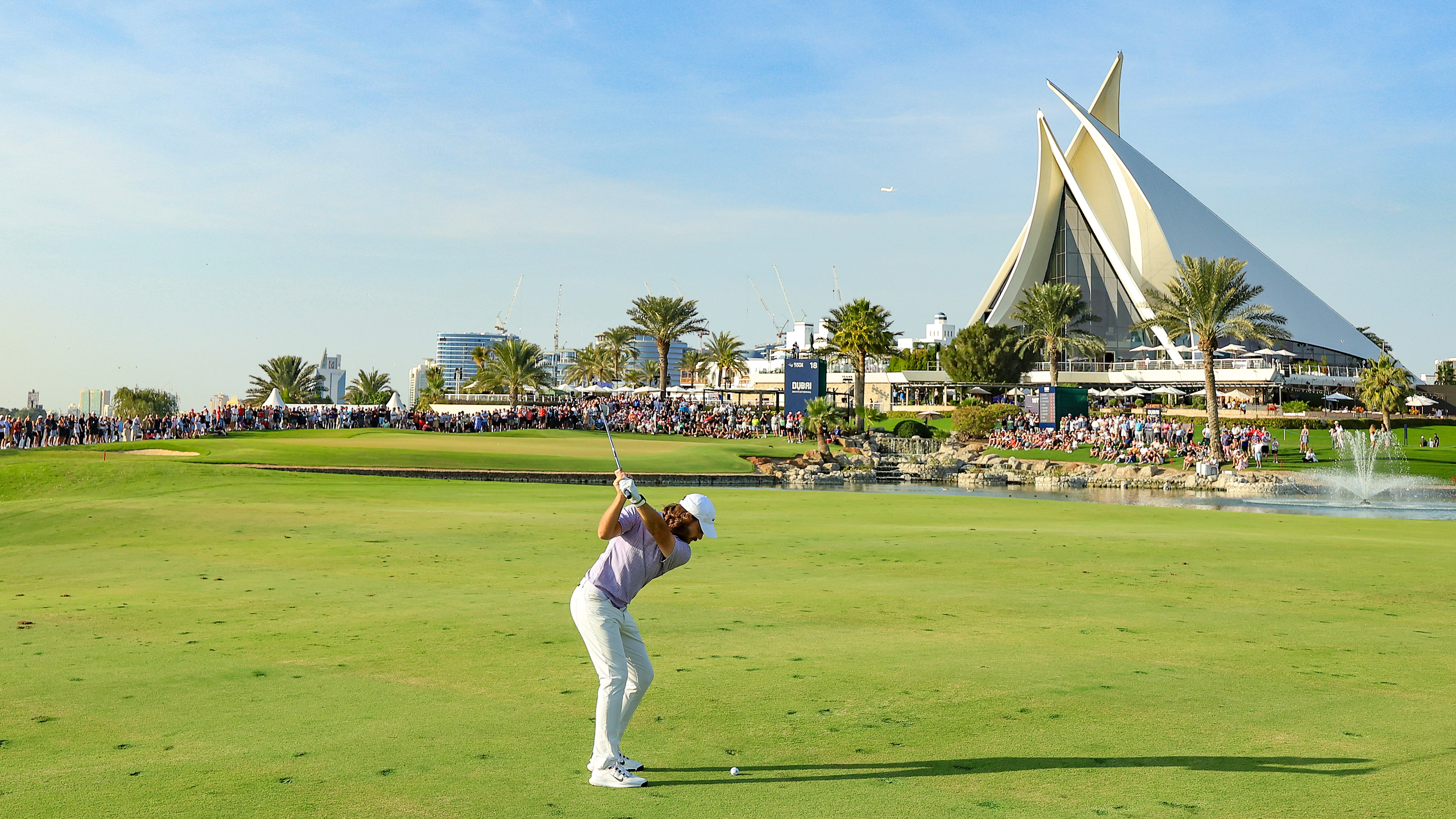 Tommy Fleetwood hitting an iron shot into the 18th green at the Dubai Invitational 2024