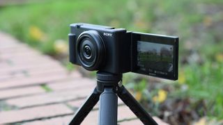 Sony ZV-1F camera on a tripod balanced on a brick wall