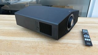 Sony Bravia Projector 9 on a light wood table next to a remote control