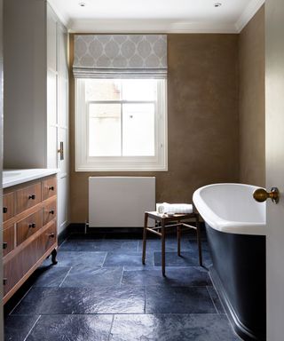 Neutral bathroom with roll top bath in elegant period London townhouse