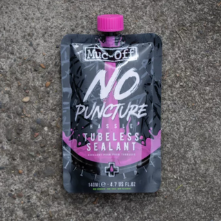 A bottle of Muc-Off No Puncture Hassle on a concrete background