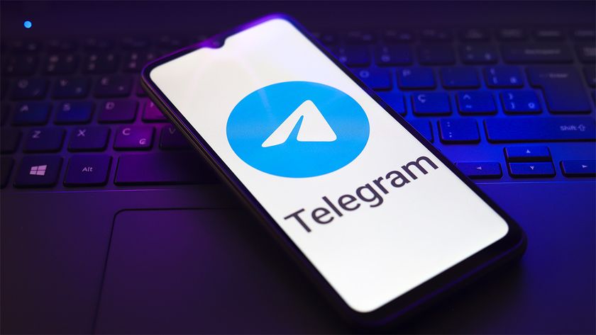 Telegram logo displayed on phone screen, with phone resting on keyboard