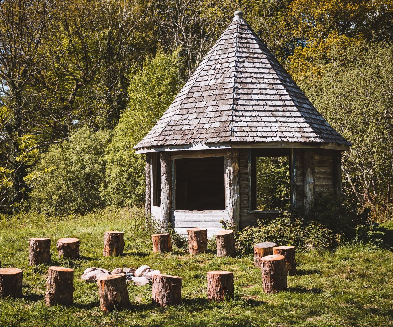 An outdoor hut and seating area made of wooden blocks around a fireplace