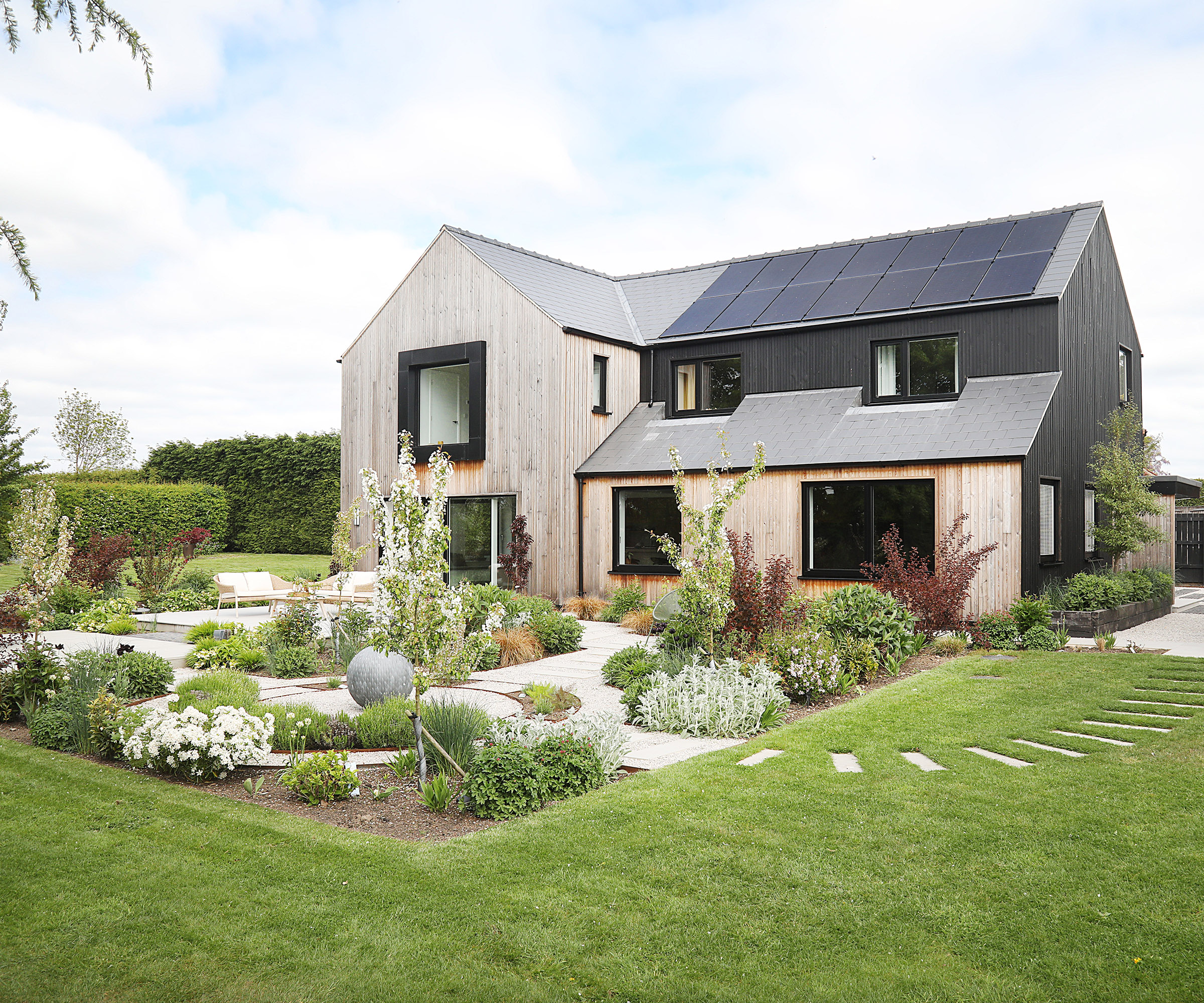 Exterior view of a newly renovated detached home with fully landscaped garden. Clad in timber and black