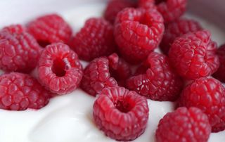A close up of fresh raspberries on top of yogurt
