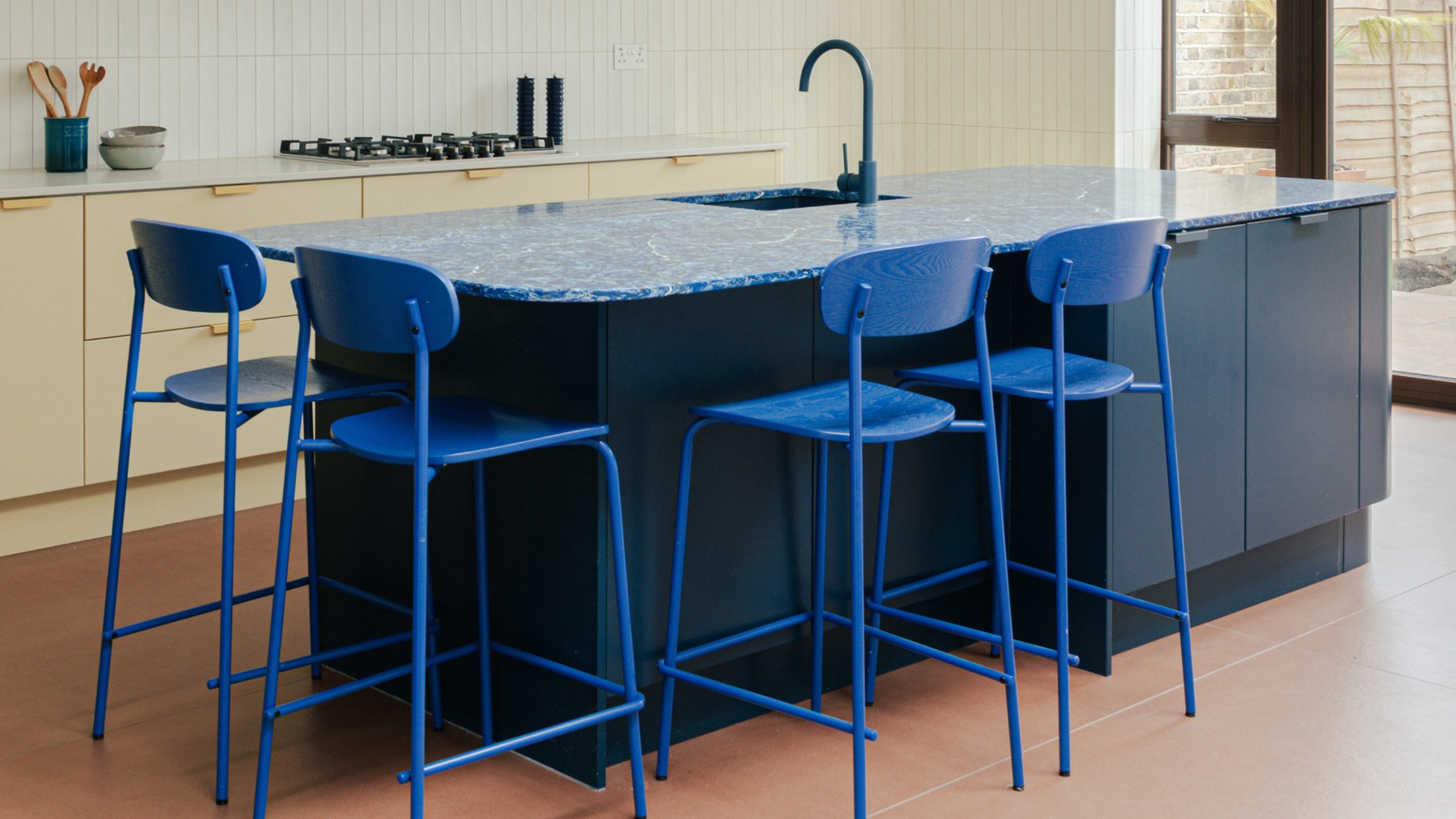 Modern kitchen with blue countertops, matching blue stools, and blue taps