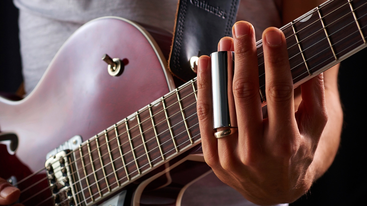 A man plays a steel slide on a Gretsch guitar