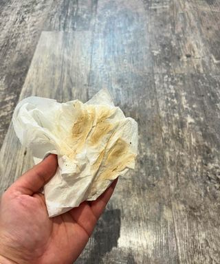 dirty white tissue held in my hand against the background of my gray bathroom linoleum floor