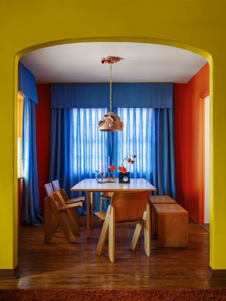 a orange painted dining room with blue curtains and pelmet