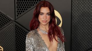 Dua Lipa smiling and posing for the Grammys red carpet.