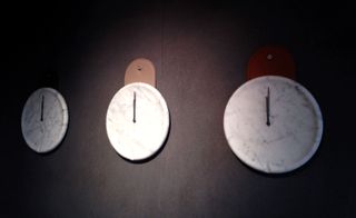 Three wall clocks made of marble with a round leather hanger.