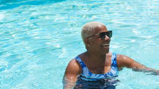 Woman lying in a swimming pool with sunglasses on, about to go swimming
