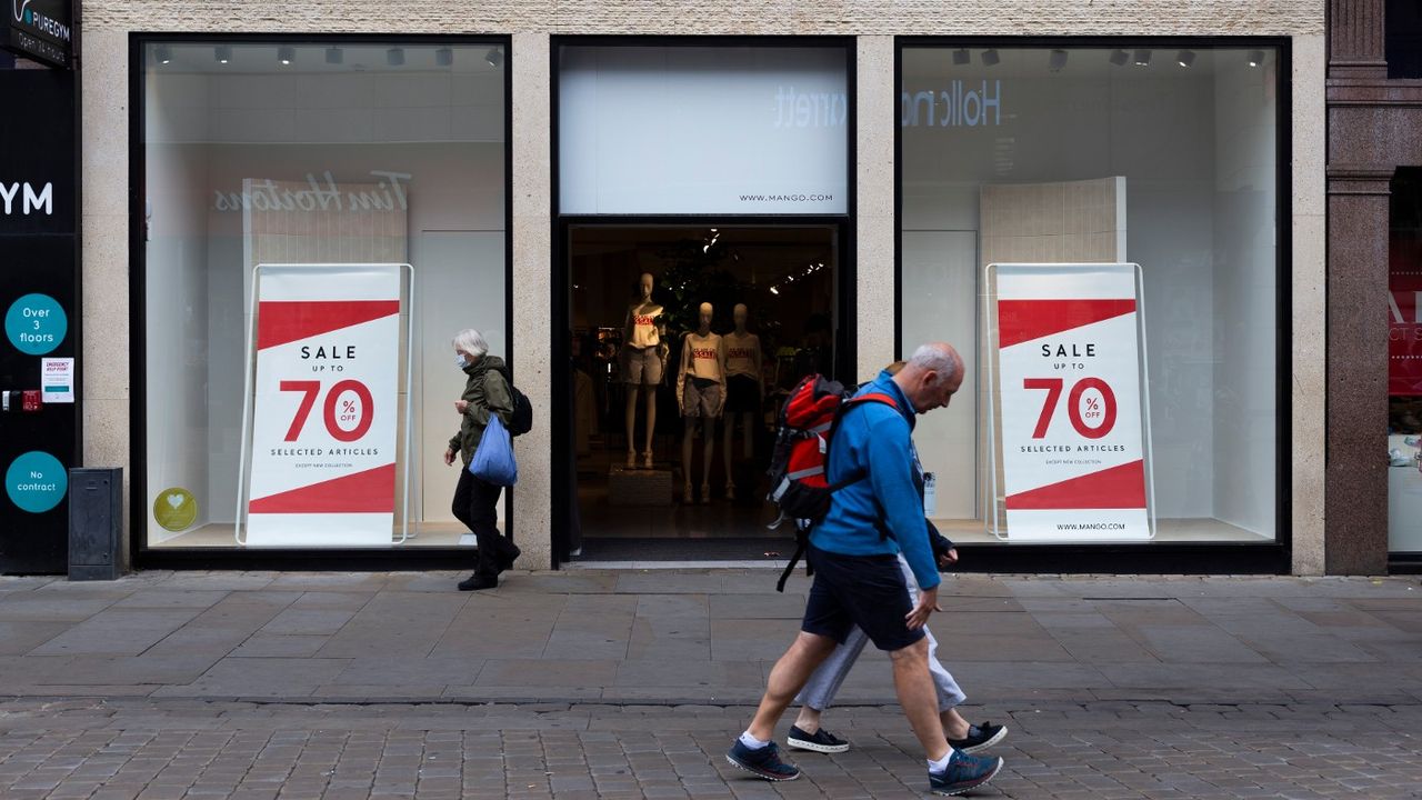 Pedestrians pass a shop in Manchester