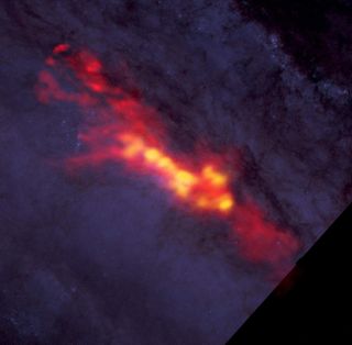 This view of the starburst galaxy NGC 253 by the ALMA array in Chile shows an envelope of carbon monoxide gas (red), which surrounds regions of active star formation (yellow). ALMA data are superimposed on an image by NASA's Hubble Space Telescope that covers part of the same region.
