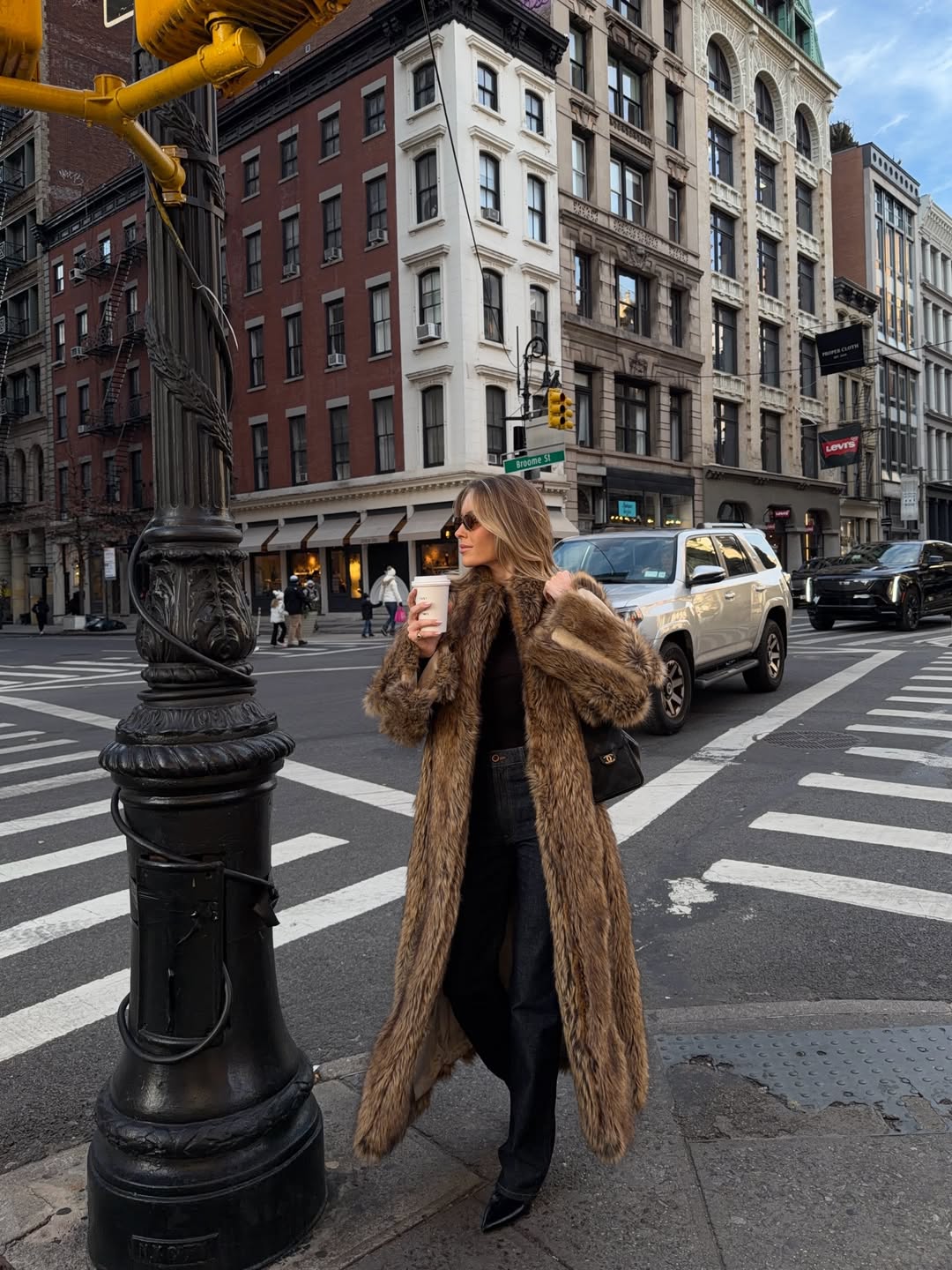 Woman wearing a brown fur coat over an all-black outfit.