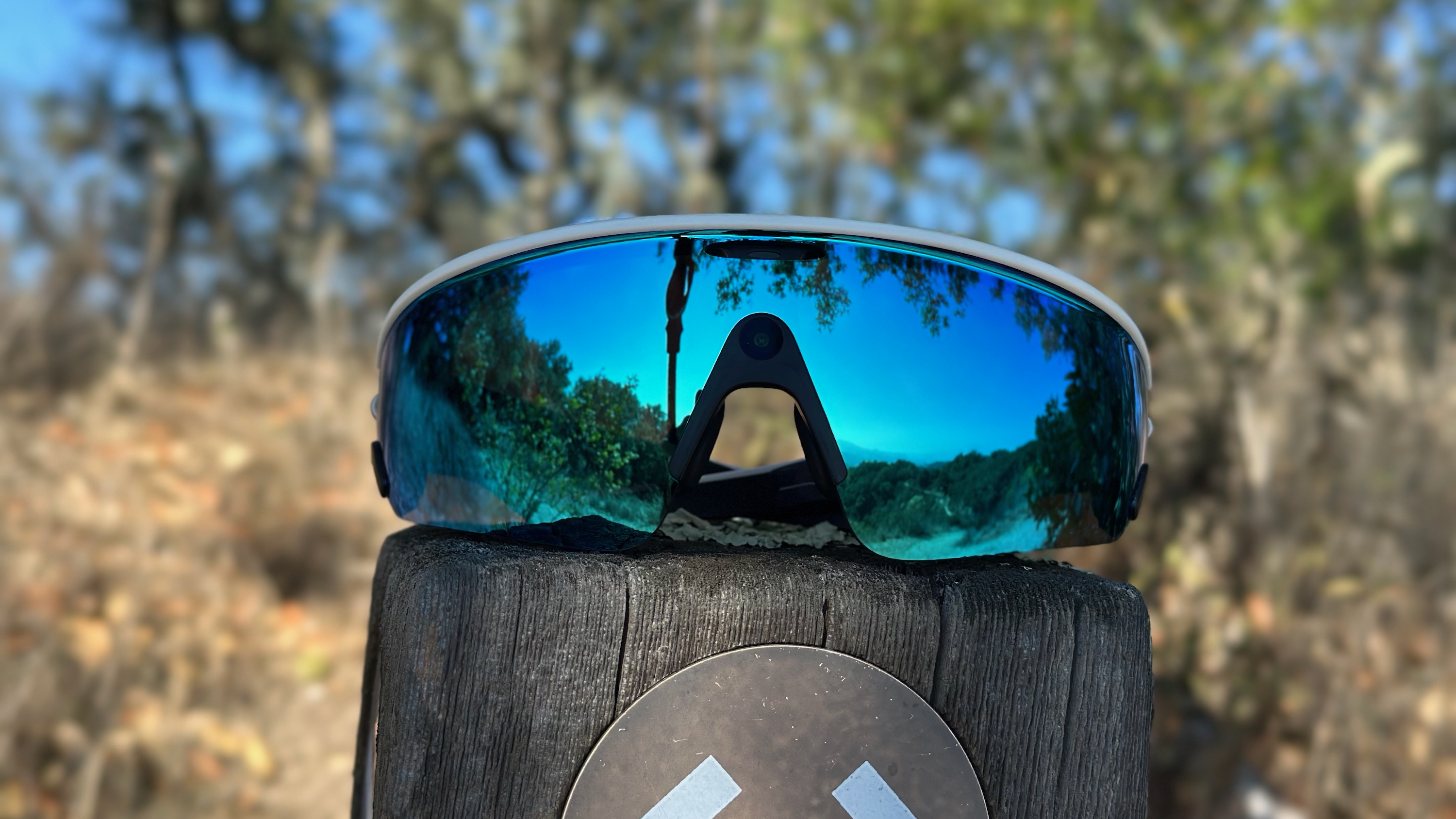 The Oakley Meta Vanguard sitting atop a wooden trailhead with trees behind it.