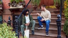 A stock photo of friends sitting on the stoop talking. 