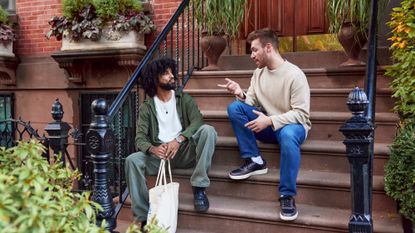 A stock photo of friends sitting on the stoop talking.