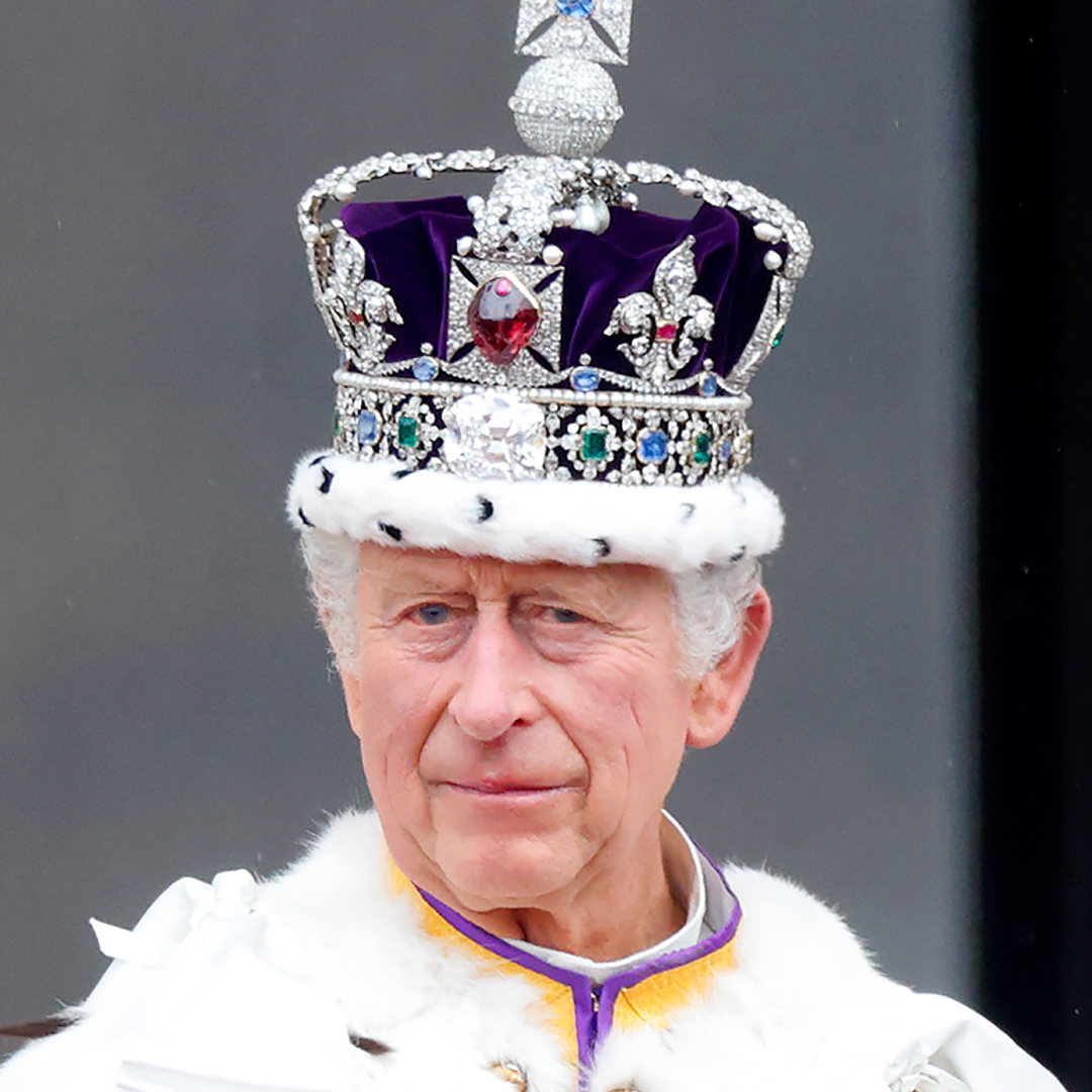 King Charles III wears a giant crown and watches an RAF flypast from the balcony of Buckingham Palace following his and Queen Camilla's Coronation at Westminster Abbey on May 6, 2023
