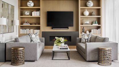 Living room with two neutral sofas facing across a coffee table and wall of shelves