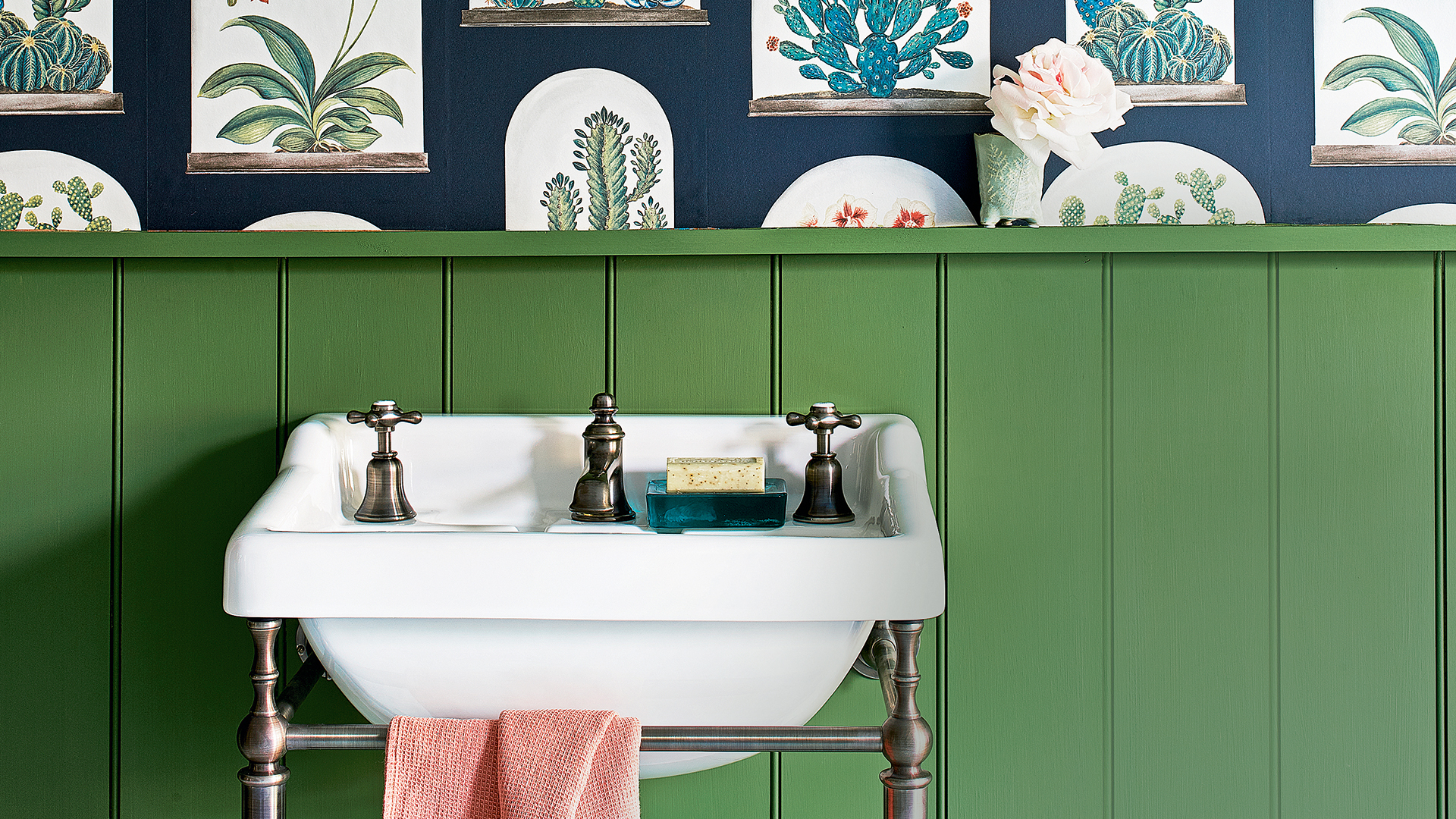 Traditional sink with an iron towel rail in a green panelled cloakroom
