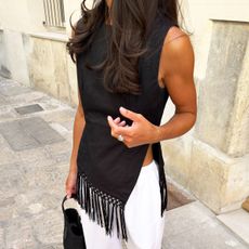 Woman in black fringe top and white pants