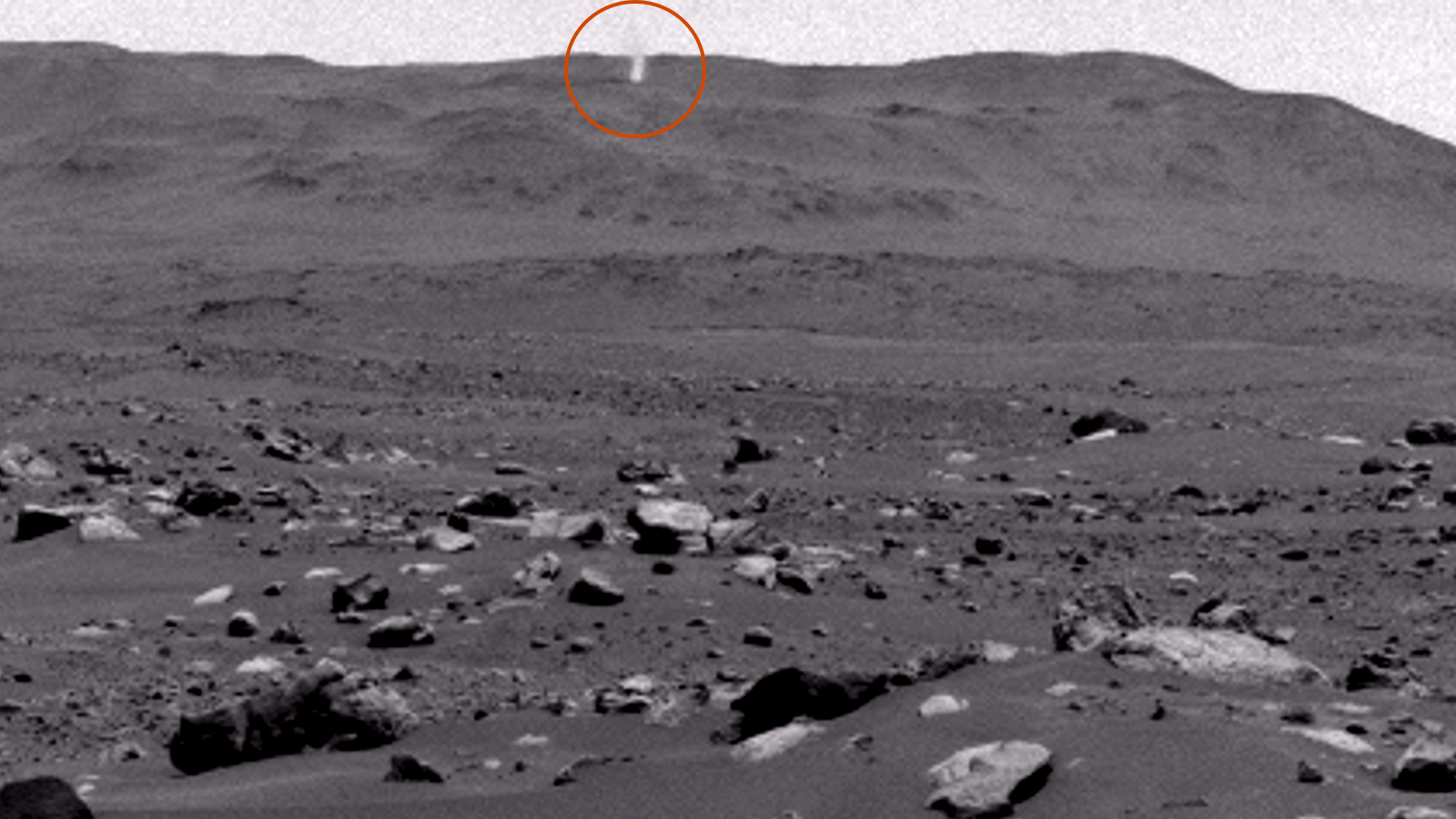 A black and white image of the surface of Mars with a small twister on the horizon (circled)