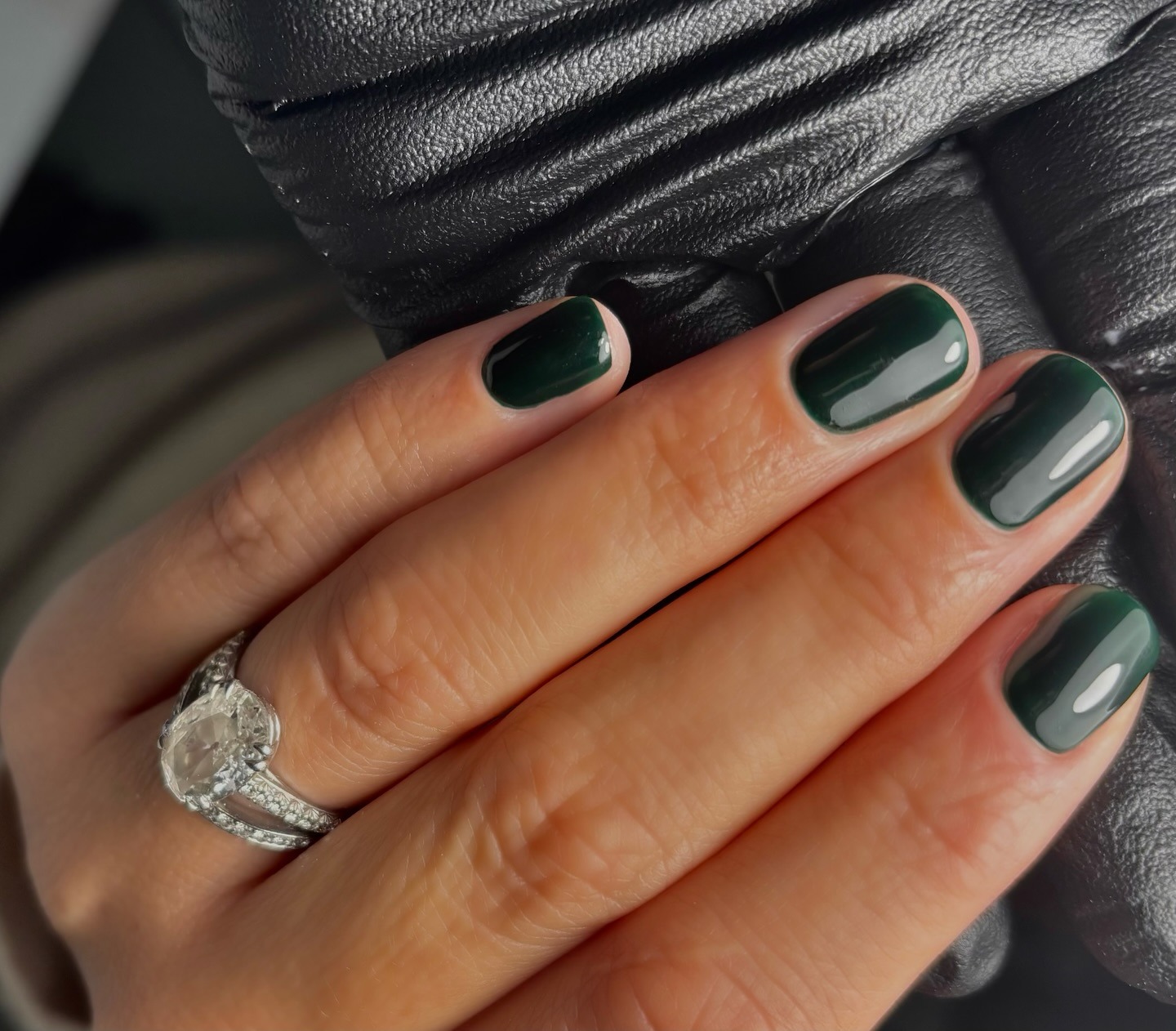 A close-up shot of a deep, forest green manicure