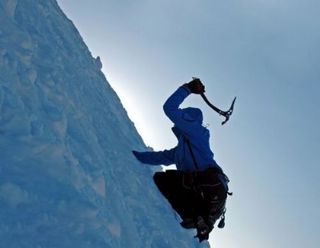 A Synnott Mountain Guides climber uses an ice pick to scale an ice-covered slope.