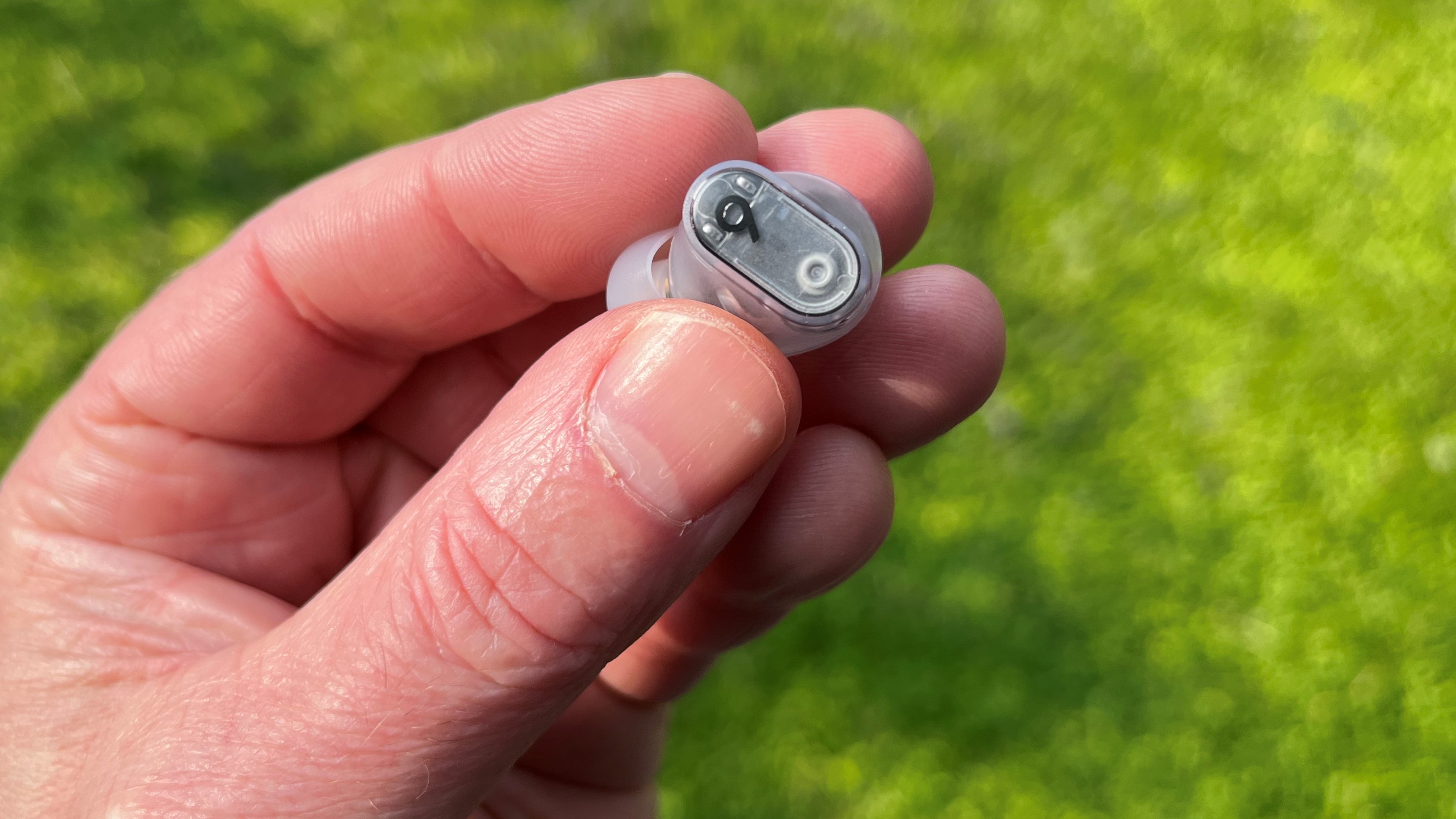 Beats Studio Buds Plus bud held in hand against green background