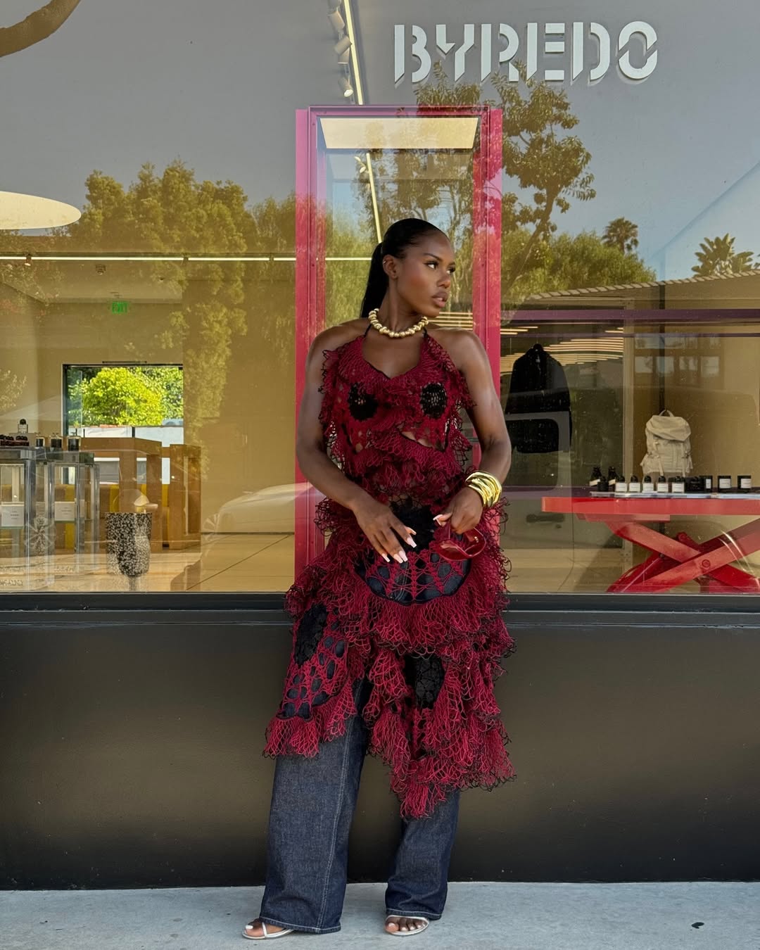 Indya Brown wears dress over jeans and beaded necklace