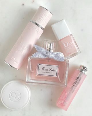 Miss Dior perfume on a marble table with other Dior beauty products