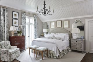 Main bedroom with bed, neutral walls, floral trail upholstery, wood floor and rug