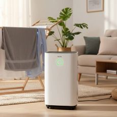 A dehumidifier from Devola in a modern lounge with laundry hanging in the background.