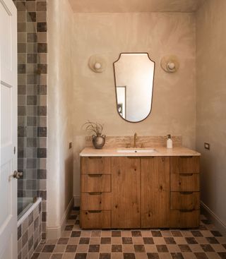 A bathroom with limewash walls, and small tiles along the floor and shower