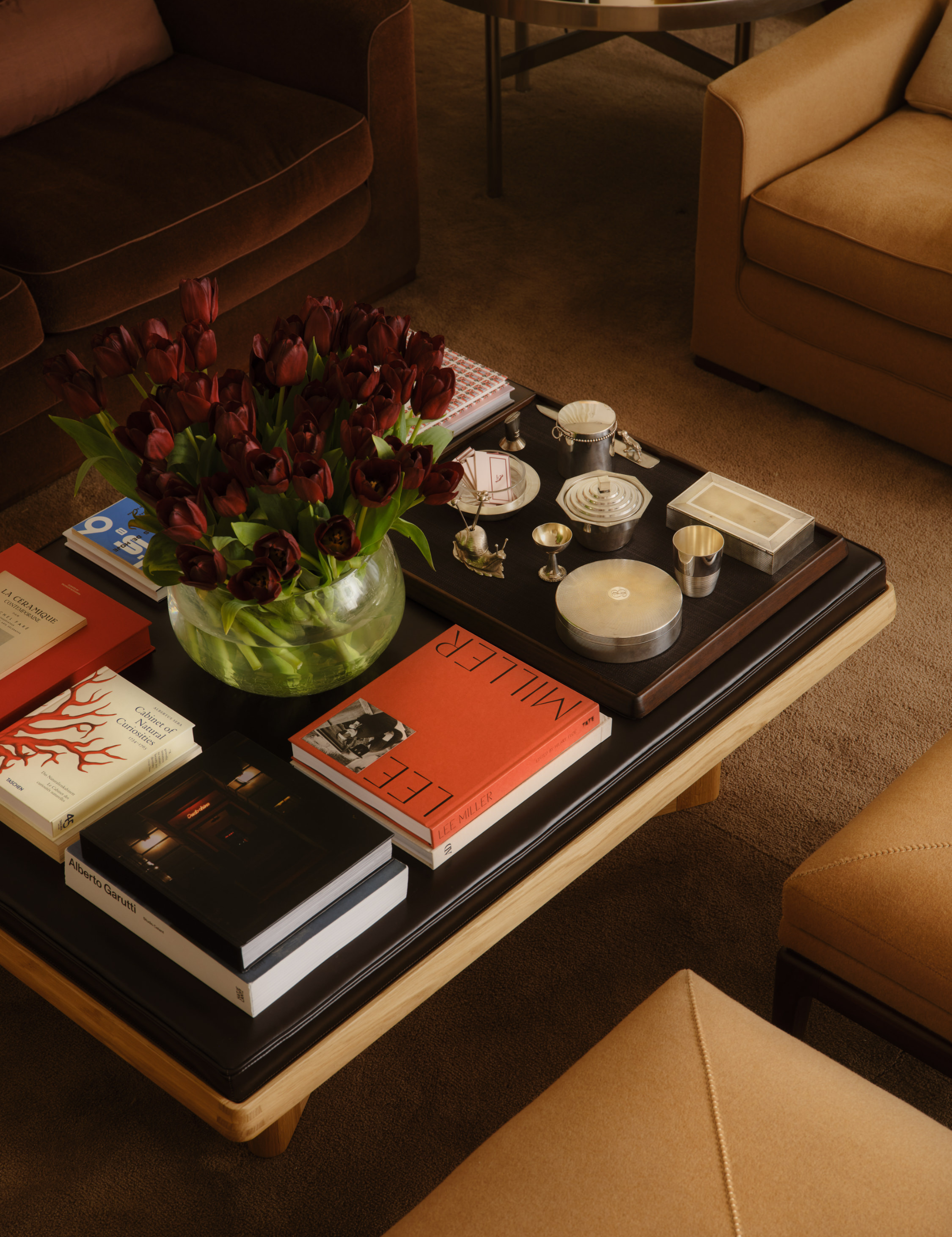 :eather-topped coffee table styled with stacks of coffee table books and assorted objets