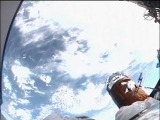 A view of Earth below from the helmet camera of Japanese spacewalker Akihiko Hoshide on Aug. 30, 2012. The gold, cylindrical spacecraft parked to the right in the photo is the Japanese robotic HTV-3 cargo freighter.