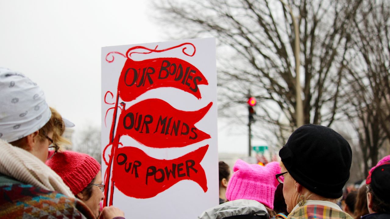 Crowds of women and men holding protest signs march through the streets during the Women&#039;s March on Washington, D.C.. Prominent sign says, &quot;Our Bodies, Our Minds, Our Power.&quot; Protest. March. Community. Togetherness.