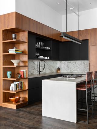Kitchen with wood and black wall units surrounding a marble splashback, marble island and open corner shelving