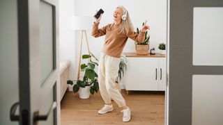 Woman dancing at home with mobile phone