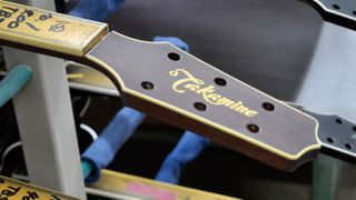 The flowing script of the Takamine logo graces the headstocks of guitars under construction