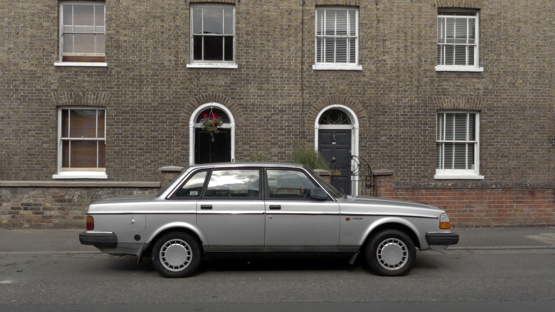 A vintage silver car in front of terrace housing shot on an Kandao QooCam 3 Ultra 360 camera