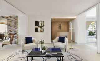 Communal area with cream chairs with blue cushions and a coffee table. Geometric artwork on the walls