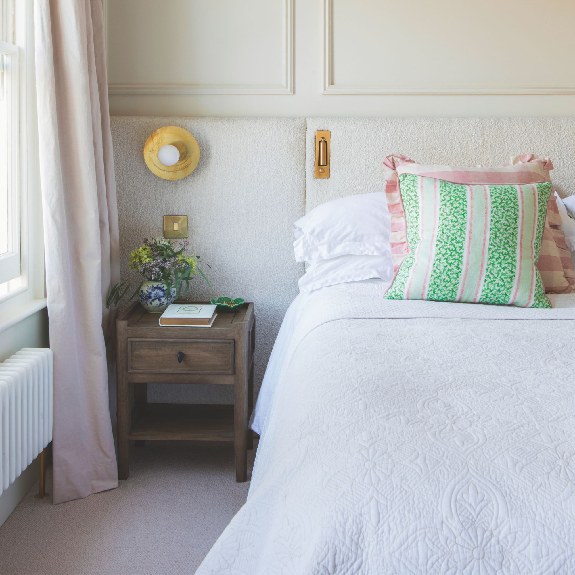 Cream panelled bedroom with bed and white bedding, including pink and green cushions on the bed