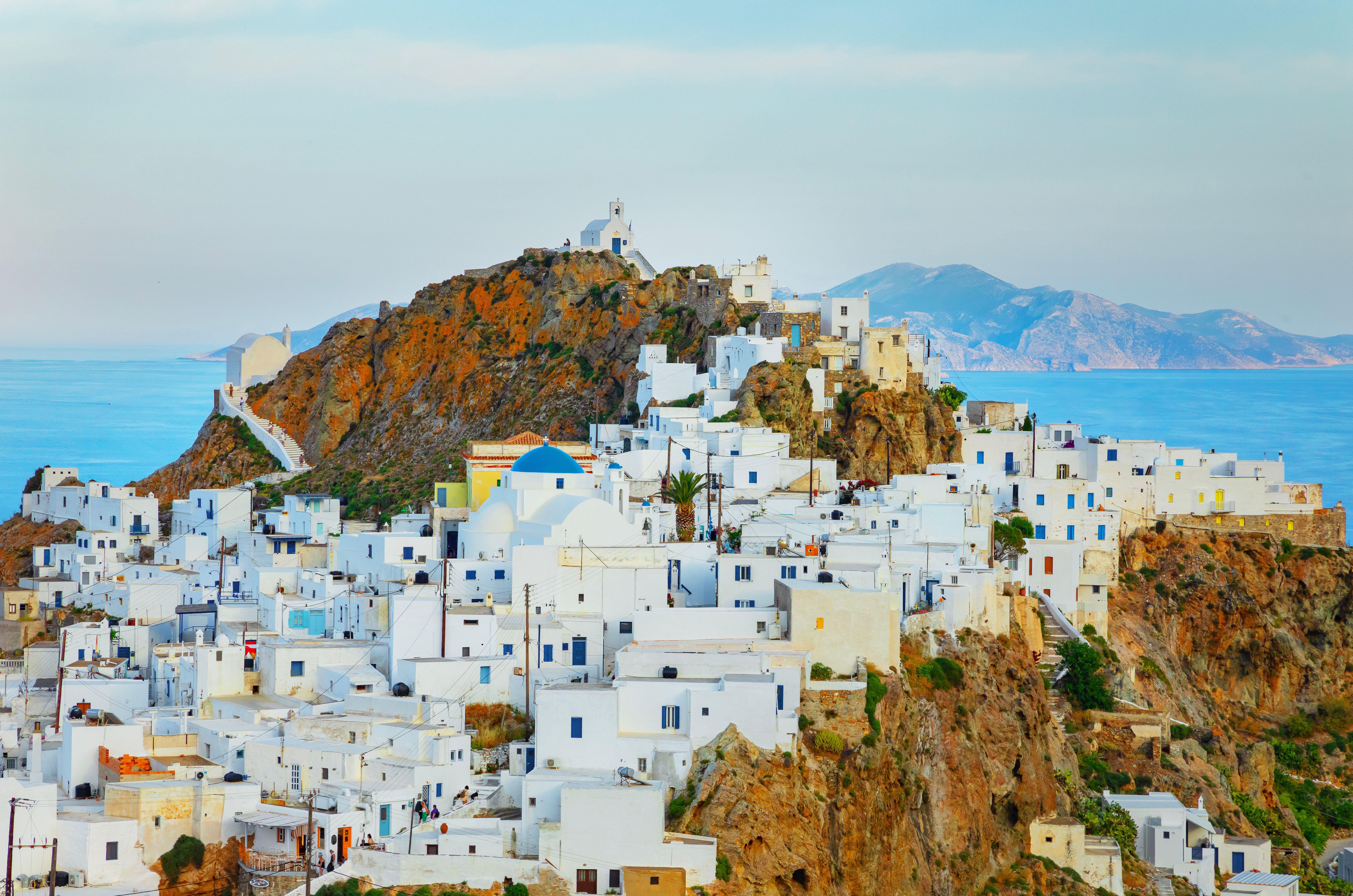 A cluster of white buildings built into a hill overlooking the sea