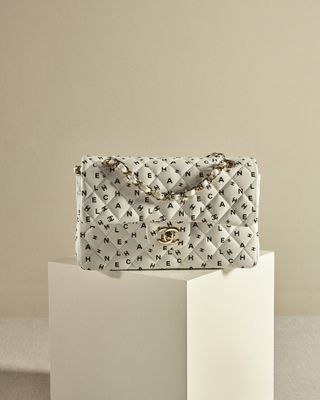 The iconic Chanel Flap bag in white with black letters scattered across the exterior
