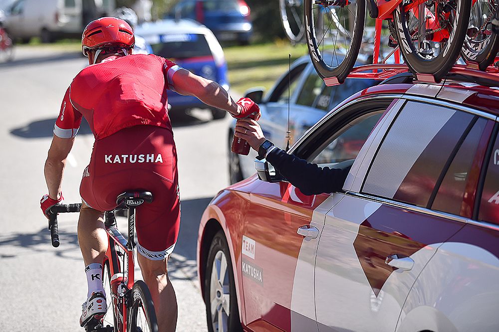 A Katusha rider takes a hand up form the team car.