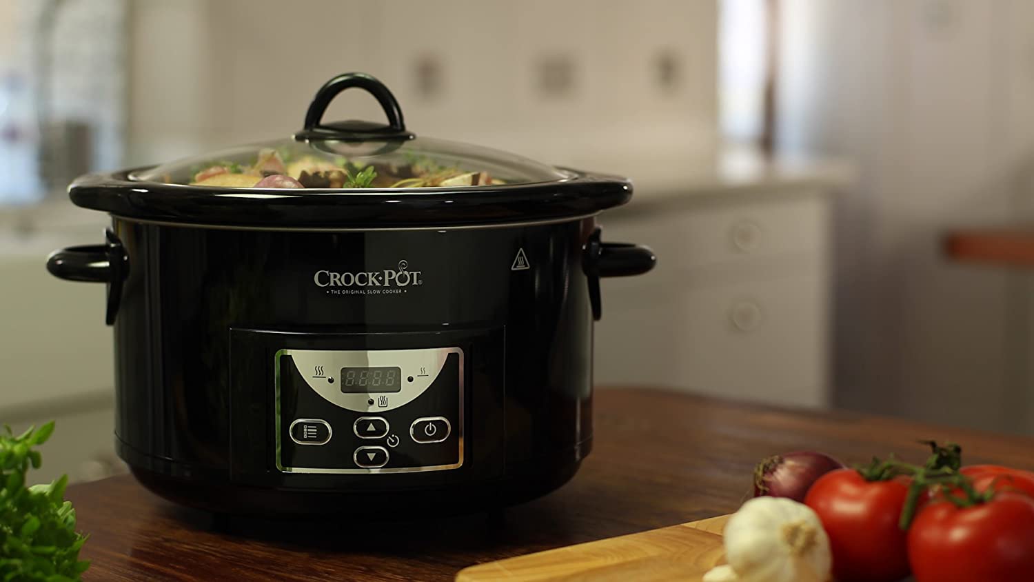 Bästa slowcooker: En svart slowcooker från Crock-pot står på en köksö med lite grönsaker framför sig.
