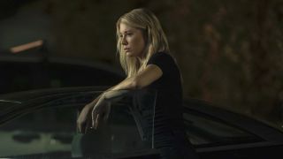 Jennifer Holland's Emilia Harcourt standing solemnly by her car in Peacemaker